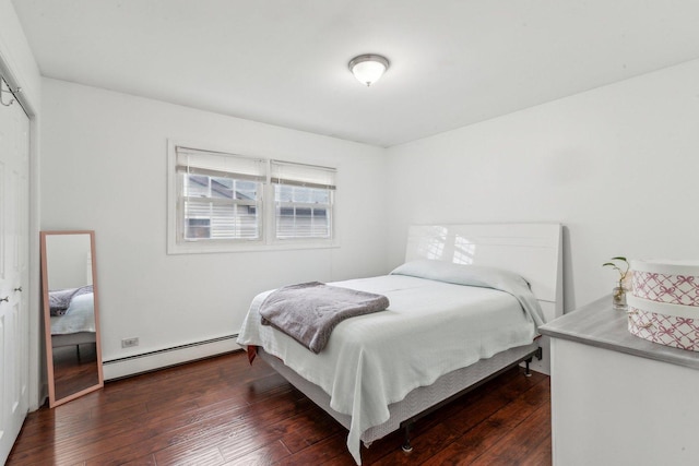 bedroom with a baseboard heating unit, dark wood-type flooring, and a closet