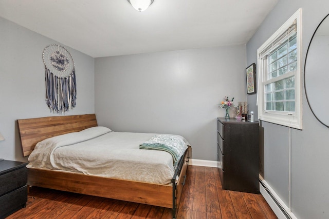 bedroom featuring a baseboard heating unit, dark wood-type flooring, and baseboards