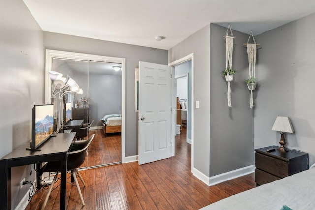 bedroom with wood-type flooring, baseboards, an office area, and a closet