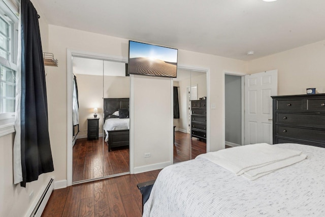 bedroom featuring baseboard heating, wood finished floors, baseboards, and a closet