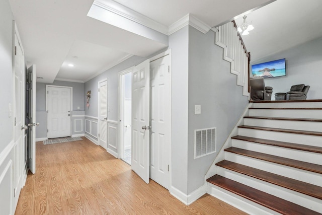 hallway with crown molding, stairway, light wood-type flooring, wainscoting, and recessed lighting