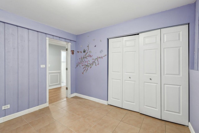 unfurnished bedroom with light tile patterned floors, baseboards, and a closet