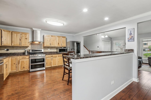 kitchen with stainless steel appliances, wall chimney exhaust hood, light brown cabinetry, dark wood-style floors, and decorative backsplash