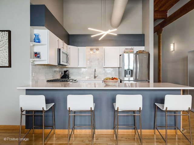 3323 N Paulina St Unit 5F, Chicago, IL 60657 - kitchen featuring appliances with stainless steel finishes, a peninsula, white cabinets, open shelves, and a sink