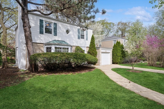 colonial home with an attached garage, driveway, a front lawn, and stone siding