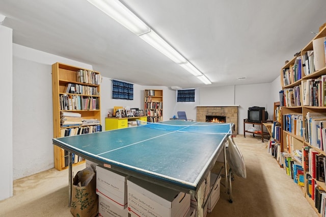 recreation room with a warm lit fireplace and light carpet