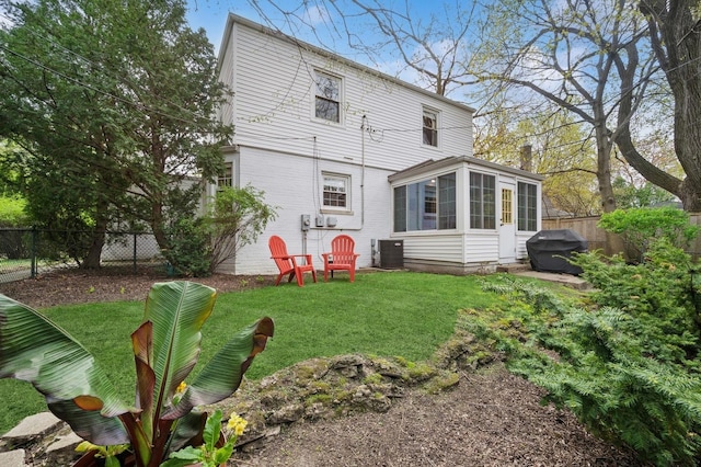 rear view of house with a sunroom, a fenced backyard, a lawn, and cooling unit