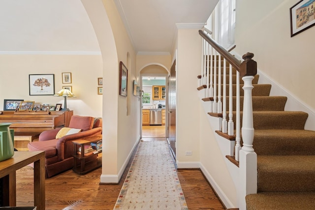 interior space with arched walkways, baseboards, wood finished floors, ornamental molding, and stairway