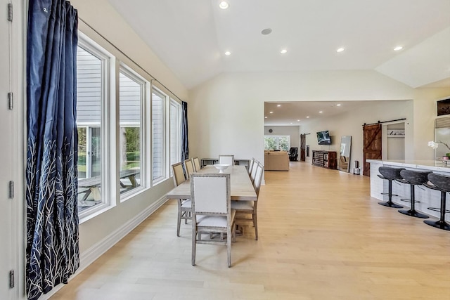 dining space with recessed lighting, a barn door, light wood-style floors, and vaulted ceiling