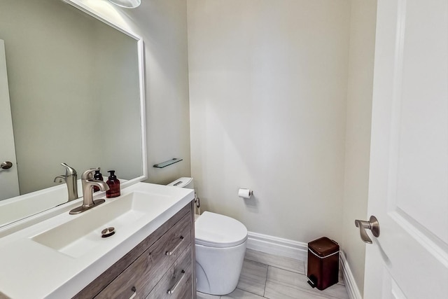 half bath featuring toilet, baseboards, and vanity