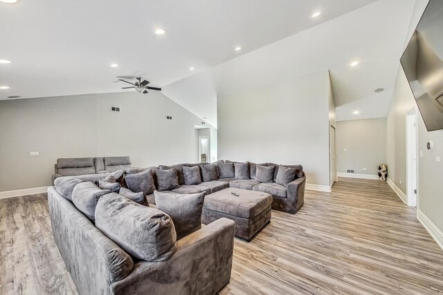 living room with baseboards, light wood-style floors, vaulted ceiling, and a ceiling fan