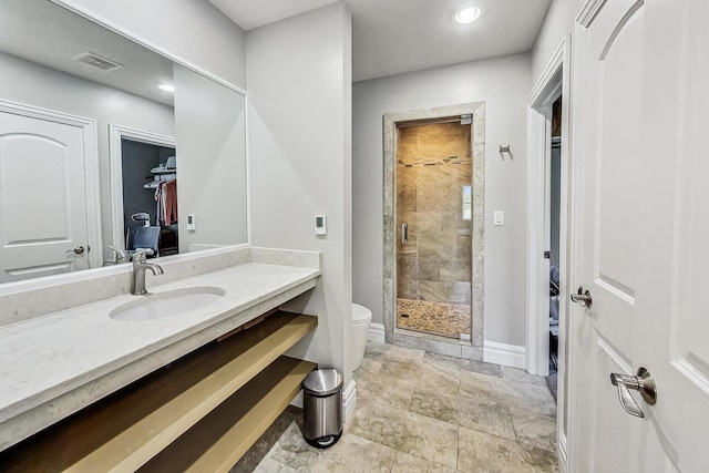 bathroom with vanity, baseboards, toilet, a shower stall, and visible vents