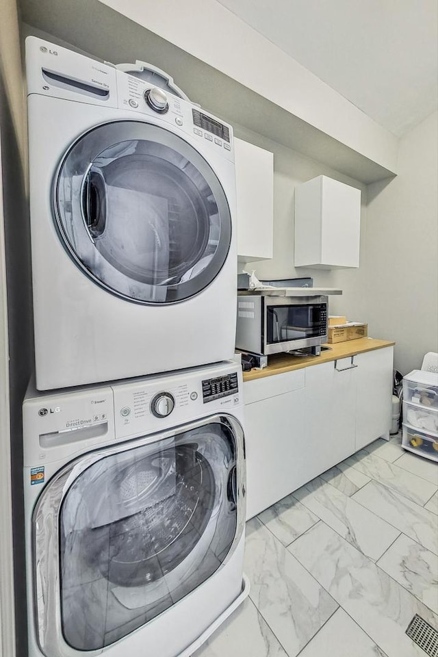 washroom with visible vents, marble finish floor, and stacked washer / dryer