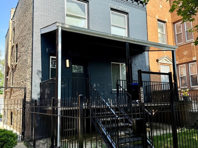 7042 S Eberhart Ave, Chicago, IL 60637 - view of property featuring brick siding, a porch, a fenced front yard, and stairs