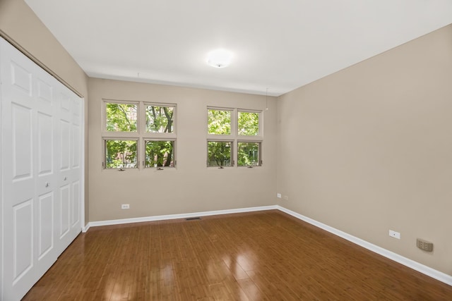 unfurnished bedroom with baseboards, dark wood finished floors, and a closet