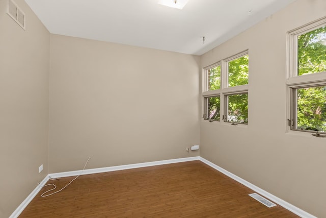 spare room with baseboards and dark wood-type flooring