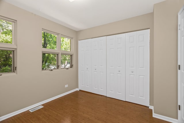 unfurnished bedroom with baseboards, wood finished floors, and a closet