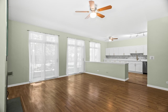 unfurnished living room featuring a ceiling fan, dark wood finished floors, and baseboards