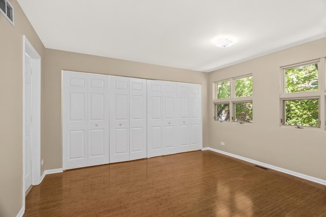 unfurnished bedroom with baseboards, dark wood-style floors, and a closet