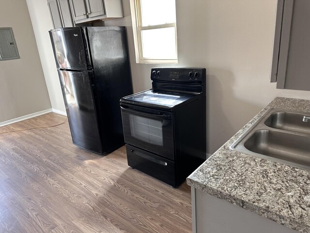 4107 W 16th St, Chicago, IL 60623 - kitchen featuring black appliances, a sink, light wood-type flooring, electric panel, and light countertops