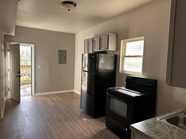 4107 W 16th St, Chicago, IL 60623 - kitchen with black appliances, electric panel, wood finished floors, a sink, and baseboards