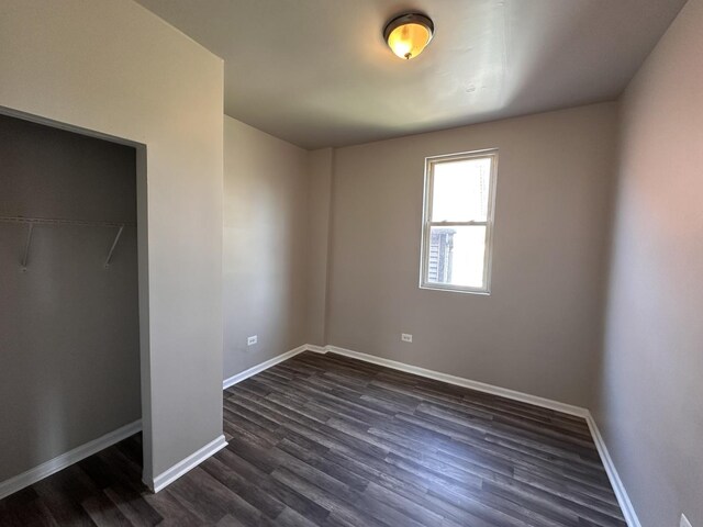 4107 W 16th St, Chicago, IL 60623 - unfurnished bedroom with dark wood-style floors, baseboards, and a closet