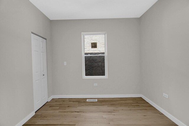 empty room featuring visible vents, baseboards, and wood finished floors