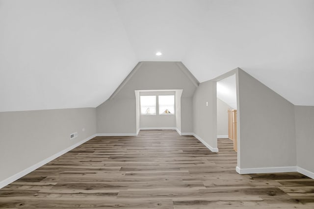 additional living space with visible vents, recessed lighting, wood finished floors, lofted ceiling, and baseboards