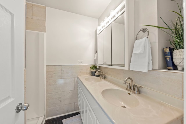 full bath with double vanity, a sink, wainscoting, and tile walls