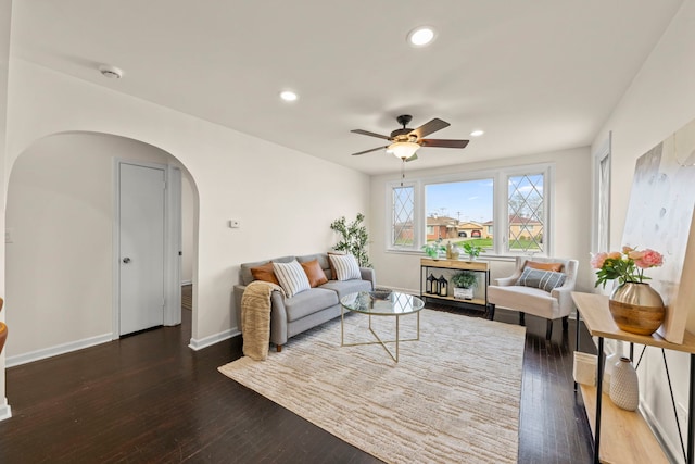 living area featuring baseboards, arched walkways, ceiling fan, and hardwood / wood-style floors