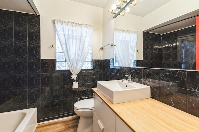 3449 N Oak Park Ave, Chicago, IL 60634 - bathroom featuring a bathing tub, tile walls, toilet, vanity, and wood finished floors