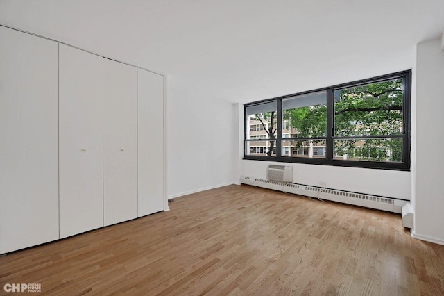 33 E Cedar St Unit 3H, Chicago, IL 60611 - unfurnished bedroom with a baseboard heating unit, light wood-type flooring, and a closet