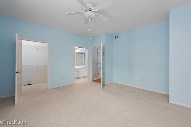 unfurnished bedroom featuring light carpet, a spacious closet, a closet, and baseboards