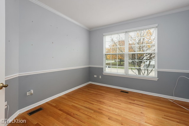 spare room with light wood finished floors, visible vents, baseboards, and crown molding