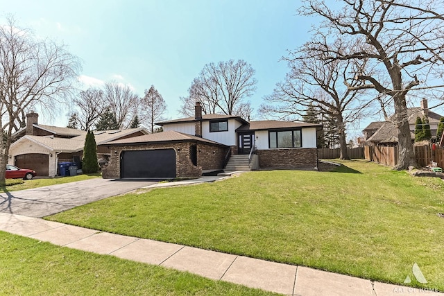 split level home with a front yard, a garage, aphalt driveway, fence, and brick siding