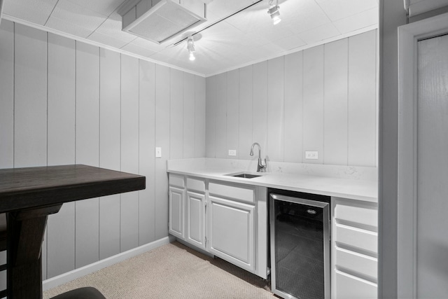 bar featuring wine cooler, carpet flooring, indoor bar, rail lighting, and a sink