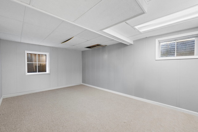 below grade area featuring baseboards, carpet flooring, and a drop ceiling