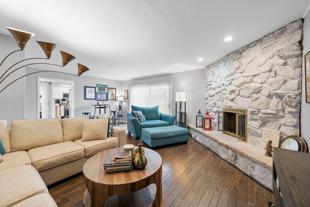 living area featuring wood-type flooring and a stone fireplace