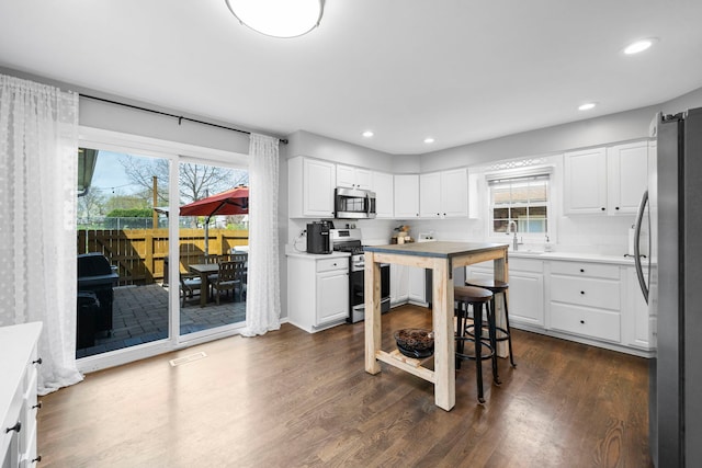kitchen with a sink, appliances with stainless steel finishes, plenty of natural light, and dark wood-style flooring