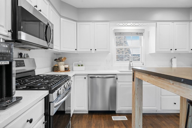 kitchen featuring a sink, white cabinetry, appliances with stainless steel finishes, and dark wood finished floors