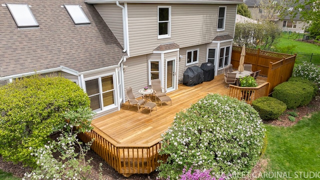 rear view of property featuring roof with shingles, fence, and a deck