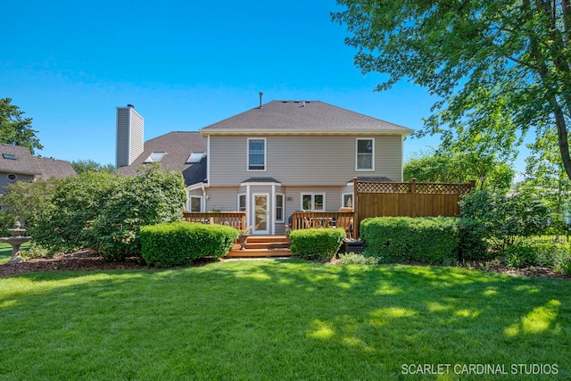back of house featuring a lawn, a chimney, and a deck