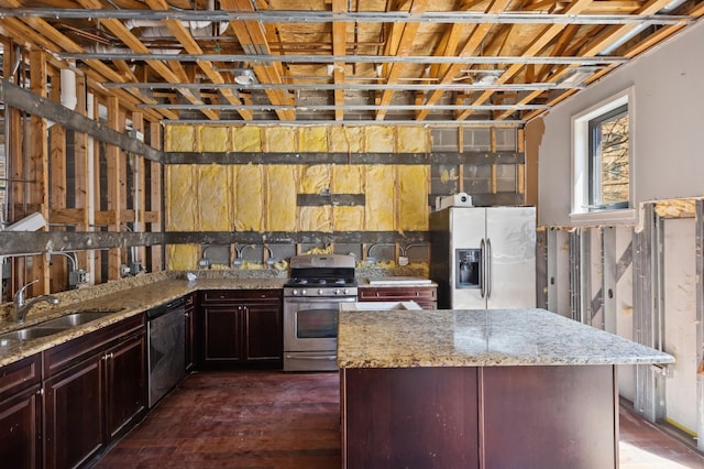 kitchen featuring appliances with stainless steel finishes, a sink, light stone counters, a kitchen island, and dark brown cabinets