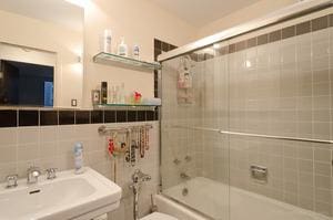 bathroom with a sink, tile walls, and bath / shower combo with glass door