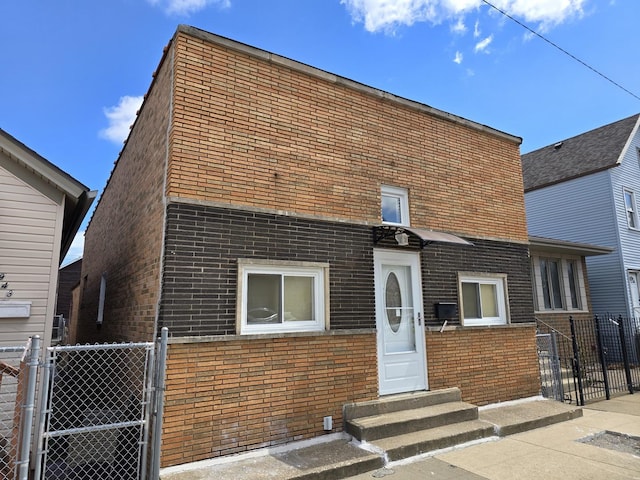 view of front of home with fence, a gate, entry steps, and brick siding