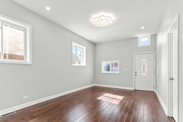 foyer entrance with baseboards, visible vents, and dark wood-style flooring