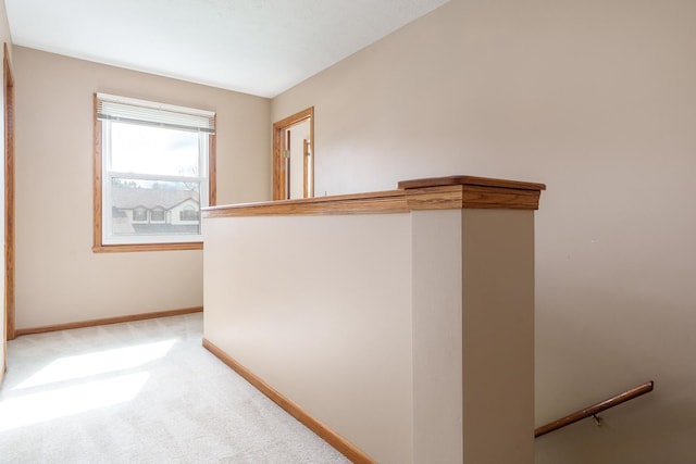 hallway featuring light colored carpet, baseboards, and an upstairs landing