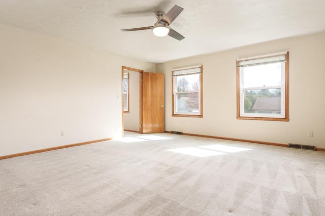 unfurnished room featuring baseboards, a ceiling fan, visible vents, and light colored carpet