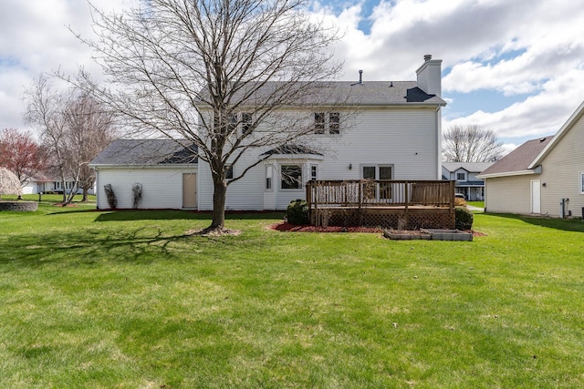 rear view of property with a chimney, a yard, and a deck