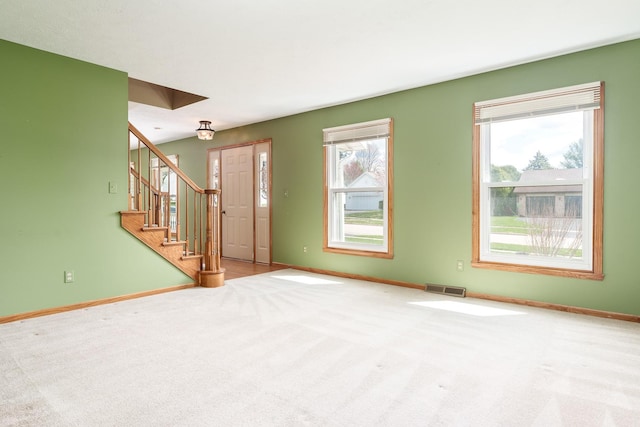 unfurnished living room with visible vents, carpet flooring, baseboards, and stairs